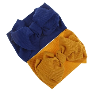 Close-up of soft baby fabric headbands with large textured bows in navy blue and mustard yellow