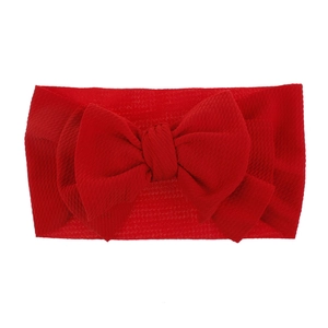 Close-up of a bright red baby headband with a large bow and soft waffle texture