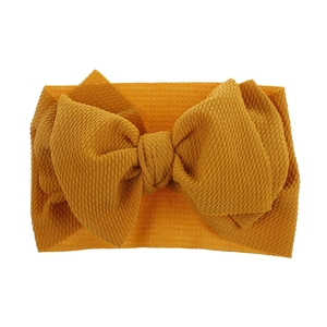 Detail view of mustard yellow baby headband featuring textured waffle fabric and large bow