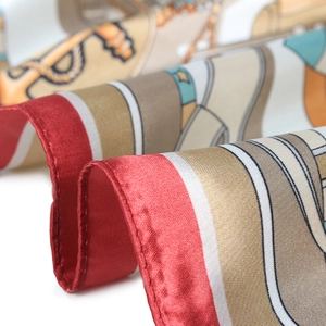 Close-up of elegant satin scarf texture with intricate patterns and red border