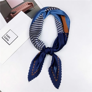 Détail d'un foulard plissé bleu au toucher soie avec motifs géométriques et nœud