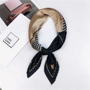 Détail d'un foulard plissé noué en nœud aux motifs géométriques noir et doré