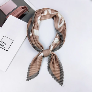 Détail d'un foulard plissé noué avec lettres abstraites tons marron, gris et beige