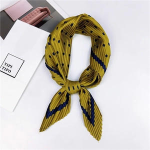 Détail d'un foulard en soie plissé jaune moutarde avec pois bleu marine et rayures