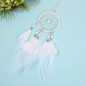 Detailed view of handmade white dream catcher with natural feathers and beads on blue background