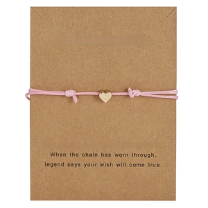 Pink woven wish bracelet with golden heart charm on a Make a Wish gift card display