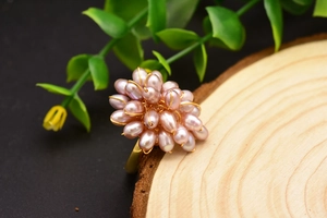Gros plan d'une bague en perles naturelles avec fleur en fil doré sur bois