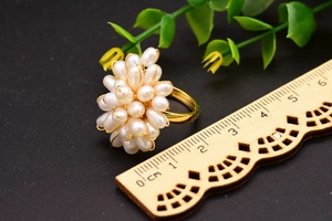 Détail macro d'une bague fleur en perles naturelles avec anneau doré et échelle