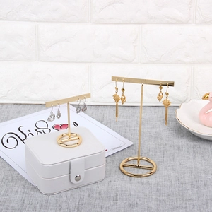 Golden T-bar metal earring stand set on a marble base for jewelry display