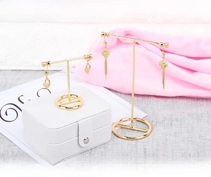 Detail of two gold metal T-shaped earring stands with circular bases for jewelry display