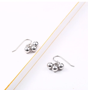 Macro shot of silver triple-bead cluster drop earrings with polished finish on white base