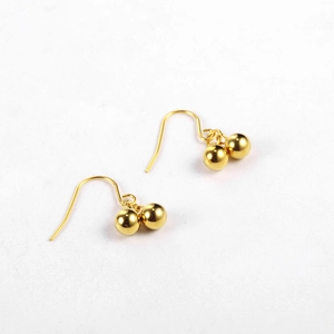 Detail of 18K gold-plated double ball drop earrings with polished metallic gloss finish