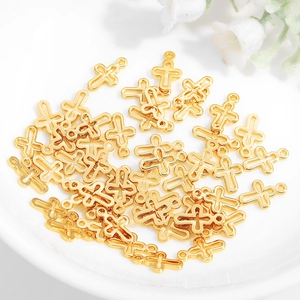 Golden metal cross pendants with hollow design for DIY jewelry making on white plate