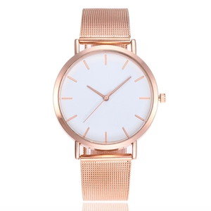 Close-up of minimalist rose gold mesh watch with white dial and metal indices