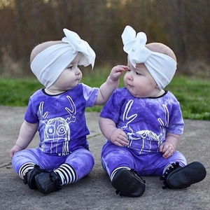Detail of purple tie-dye baby outfit with deer horn graphic and large bow headband