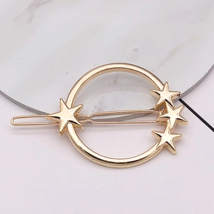 Detailed close-up of a gold metal hair clip with a minimalist star and circle design