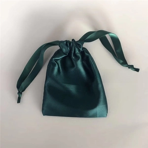 Detail of dark green satin drawstring bag with smooth silk texture and glossy finish