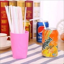 Close-up of disposable white plastic straws with colorful stripes in a pink cup