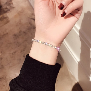 Close-up of a silver tennis bracelet featuring round-cut sparkling crystals on a woman's wrist