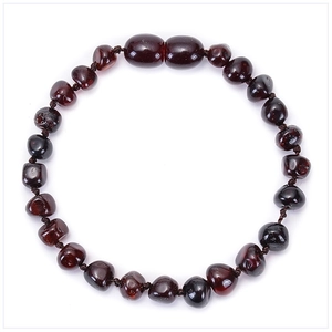 Macro view of natural Baltic amber baby bracelet with deep wine red irregular beads