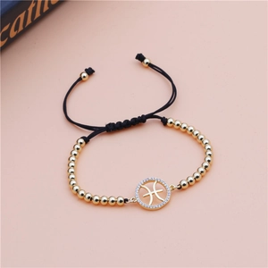 Detail of Pisces zodiac charm on braided bracelet with gold beads and white zircon