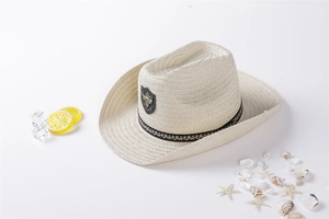 Close-up of cream straw cowboy hat with black woven band and bull metal emblem
