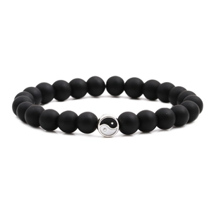 Macro view of matte black beaded bracelet featuring a Yin Yang balance symbol charm