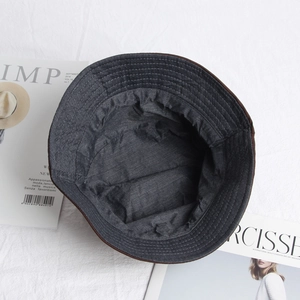 Detail view of a reversible bucket hat showing brown fabric and dark grey cotton lining