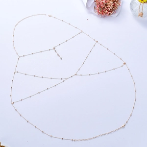 Detail of gold body chain featuring fine beads and intricate multi-layer mesh design