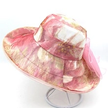 Close-up of pink floral organza sun hat with large translucent bow on a metal stand