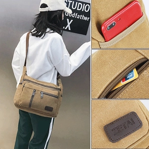 Detail view of khaki canvas crossbody bag showing multiple pockets and brand logo patch