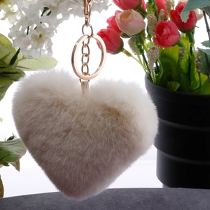 Macro shot of fluffy cream faux fur heart pendant with gold metal ring and chain