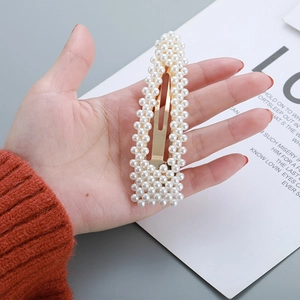 Detail of elegant gold-toned oval hair clip adorned with small white pearls