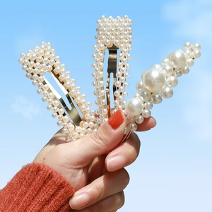 Detailed view of three pearl hair clips featuring white pearls on gold metal frames
