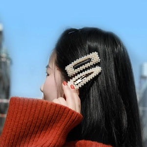 Close-up of model wearing two rectangular pearl hair clips with golden alloy base