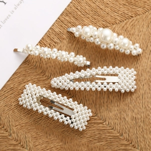 Detail of four-piece pearl hair clip set with silver metal bases on woven mat