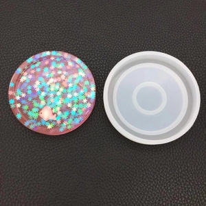 Close-up of circular silicone mold for resin craft with pink fish and floral inlay detail