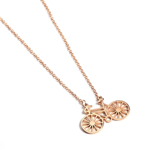 Macro detail of 18K rose gold plated bicycle pendant with polished cutout metal finish