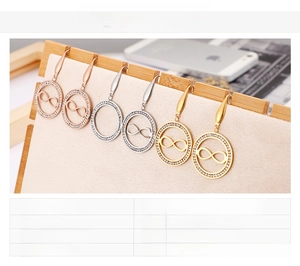 Détail de boucles d'oreilles signe infini en trois couleurs sur présentoir en bois