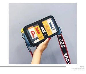 Détail du sac à bandoulière multicolore avec slogan et large sangle rouge et noire