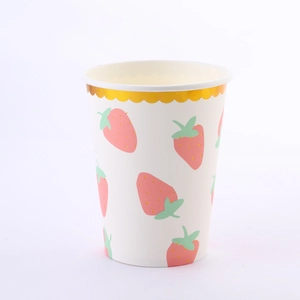 Close-up of disposable paper cup with pink strawberry patterns and scalloped gold foil rim
