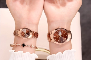 Detailed view of women's quartz watch with rose gold strap and brown sunburst dial