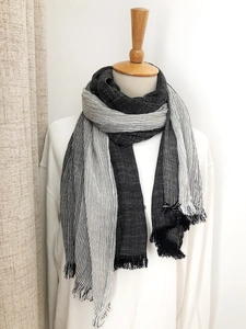 Detail of black and white striped scarf with tassels on a mannequin in soft lighting