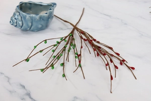 Detail of artificial Christmas berry vines with red and green fruits on marble background