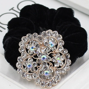 Vue détaillée d'un chouchou en velours noir orné d'une grande broche fleurie en cristal argent