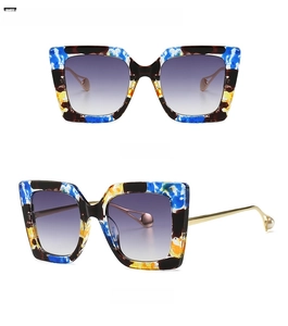 Detail of floral tortoiseshell sunglasses with purple gradient lenses and gold metal temples