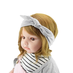 Close-up of a soft grey knotted rabbit ear headband worn by a baby on a white background