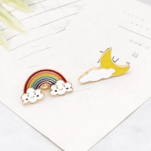 Detail of vibrant rainbow and moon cloud enamel pins on cardstock background