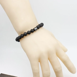 Close-up of black volcanic stone bead bracelet with a dark gray magnetic cylinder clasp