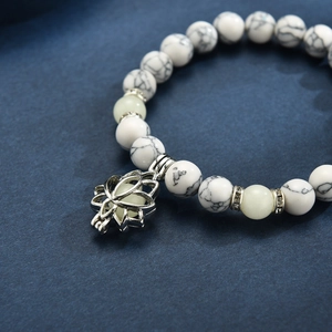 Detail of beaded yoga bracelet featuring a silver lotus charm and white marble beads
